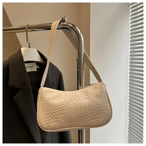 Detail shot of cream woven leather shoulder bag with gold zipper on a metal hanger