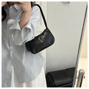 Close-up of a black woven leather hobo bag worn as a shoulder underarm bag for women