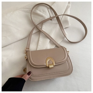 Detail of beige crossbody bag featuring a golden U-shaped clasp and fine PU leather texture