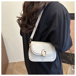 Detailed side view of white leather saddle bag with gold U-shaped buckle on female model