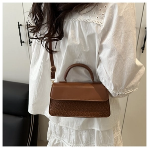 Detailed macro view of brown faux leather handbag with weave texture and gold hardware