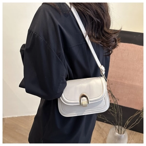 Detailed side view of white faux leather crossbody bag with a gold horseshoe buckle