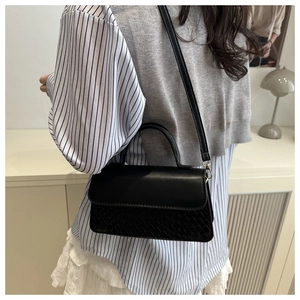 Detail of black crossbody bag featuring smooth flap and elegant snakeskin textured panel
