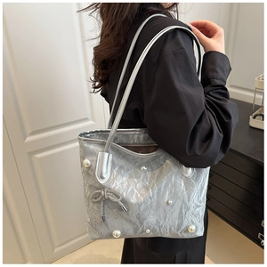 Detail of silver metallic tote bag with white pearls and woven bow charm decoration