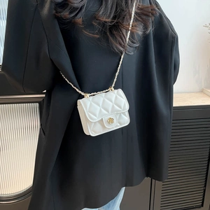 Mini white quilted crossbody bag with golden camellia lock shown on shoulder