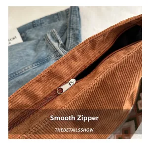 Close-up of smooth metal zipper and corduroy fabric texture on a large tote bag