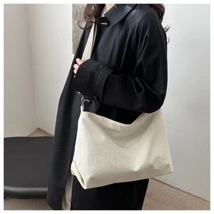 Close-up of cream corduroy tote bag with woven shoulder strap on a model's side