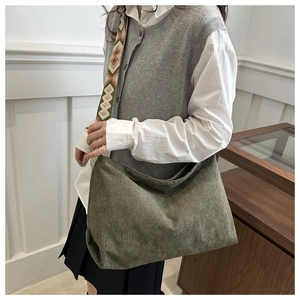 Detailed texture of olive green corduroy tote bag with ethnic embroidered strap