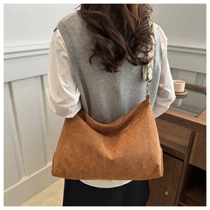 Brown corduroy tote bag with ethnic geometric patterned wide strap on a female model