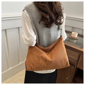 Detail of caramel corduroy tote bag showing ribbed texture and metal buckle strap