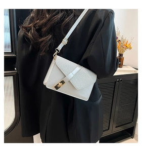 Detail of light blue envelope crossbody bag with textured flap and gold metal lock on a model