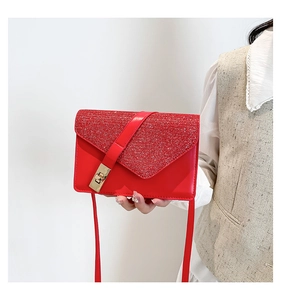 Detail of red crossbody bag with glitter flap and golden metallic clasp closure