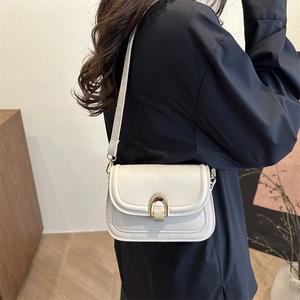Minimalist beige leather shoulder bag with horseshoe buckle shown on a model