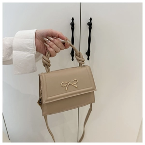 Détail du sac à main beige élégant avec boucle nœud doré et poignée nouée sophistiquée
