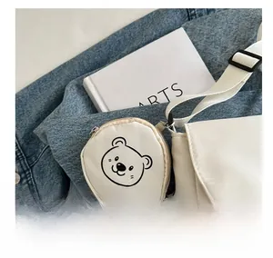Close-up of a small round cream coin purse with cartoon bear print and metal clip