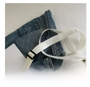 Detail of adjustable white fabric strap with black buckle on a minimalist messenger bag