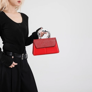 Sac bandoulière rouge avec poignée argentée et rabat à paillettes porté par un mannequin