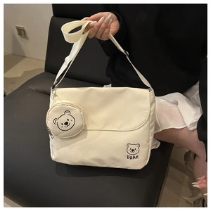 Detail of off-white canvas messenger bag with cartoon bear print and round coin purse