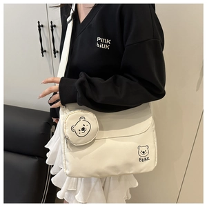 Detail of off-white crossbody messenger bag with a detachable round bear coin purse