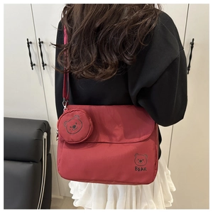 Detail of red messenger bag featuring a bear print and matching round coin purse charm