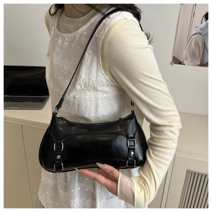 Dettaglio della borsa baguette nera lucida con fibbie argentate e borchie sulla modella