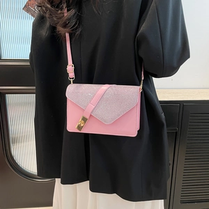 Pink envelope crossbody bag with glitter flap and gold twist lock in street style view