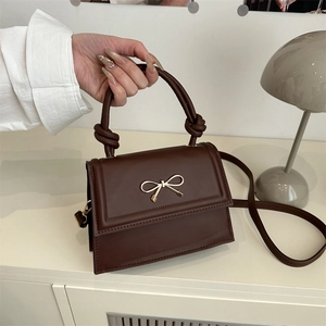 Sac trapèze en cuir mat marron avec fermoir nœud doré et poignée nouée élégante
