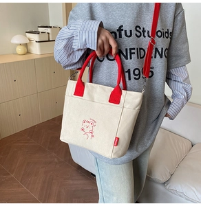Detail of canvas tote bag with red handles and cute bear print in cozy indoor setting