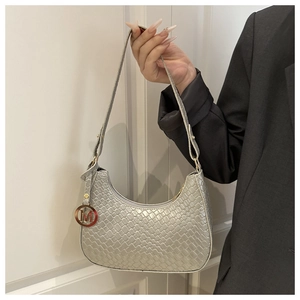 Detailansicht der silbernen geflochtenen Schultertasche mit M-Anhänger und Reißverschluss
