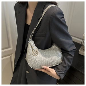 Close-up of silver hobo bag with crocodile texture and metal M pendant on model