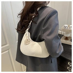 Detailed view of white woven texture shoulder bag with metallic M pendant on grey suit