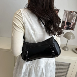 Borsa baguette nera lucida minimalista con fibbie argentate in un elegante contesto interno