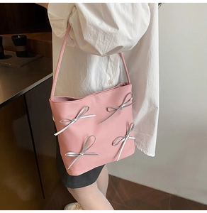 Detailed side view of pink shoulder bag with silver bow accents on PU leather strap