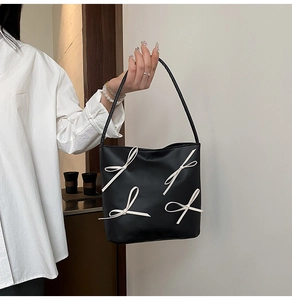 Detail der schwarzen Shopper-Tasche mit cremefarbenen 3D-Schleifen und Schultergurten