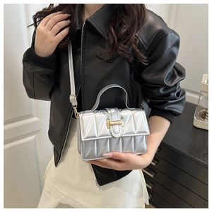 Detailed shot of metallic silver quilted bag with a sleek gold buckle and shoulder strap