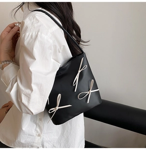 Detailed side view of black bucket tote bag with decorative cream white ribbon bows