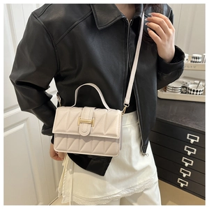 Detail of cream quilted crossbody bag with golden hardware and textured geometric pattern