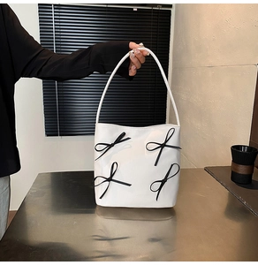 Detail of white leather shoulder bag with four decorative black ribbons and elegant handle