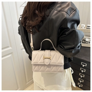 Detail of a quilted crossbody bag in beige leather with golden buckle on a model