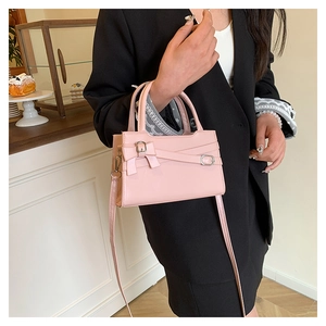 Detail of pink leather handbag featuring a decorative bow and silver metallic hardware
