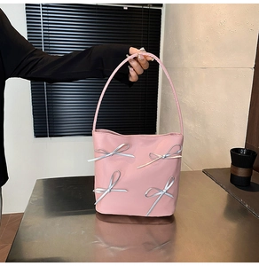Detail of pink shoulder bag with silver metallic bows and smooth leather texture