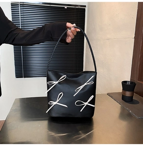 Detailed view of black PU leather shoulder bag with decorative white ribbon bows