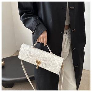 Détail de la texture tissée sur un sac en cuir crème avec fermoir en métal doré élégant
