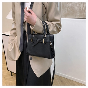 Detail van zwarte crossbodytas met strikontwerp en goudkleurige gesp op casual outfit