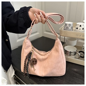 Detail of pink hobo bag with pretzel charm, woven rope, and metal key accessories