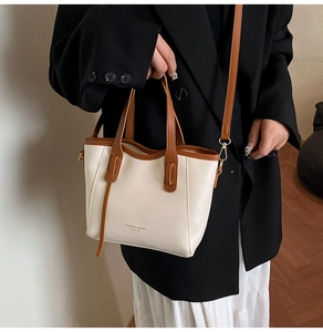 Dettaglio della borsa a secchiello beige con manici in pelle marrone e finiture dorate