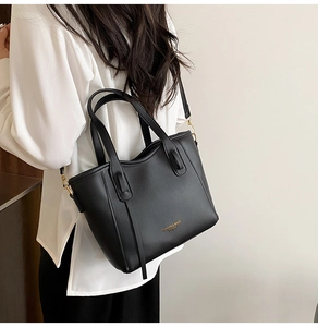 Dettaglio borsa tote in pelle nera opaca con finiture dorate e tracolla regolabile