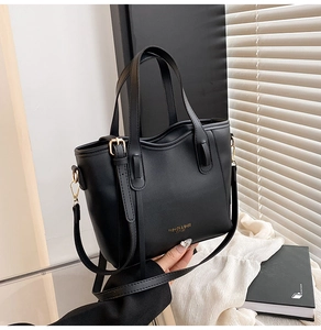 Dettaglio della borsa tote nera opaca con hardware dorato e scritta del marchio