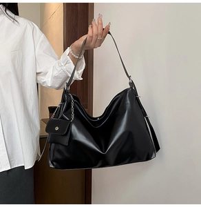 Detail einer großen schwarzen Hobo-Tasche mit silberner Kette und Mini-Taschenanhänger