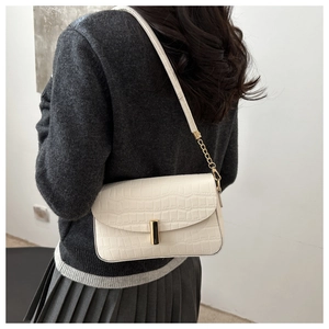 White crocodile pattern square crossbody bag with gold hardware shown on a model